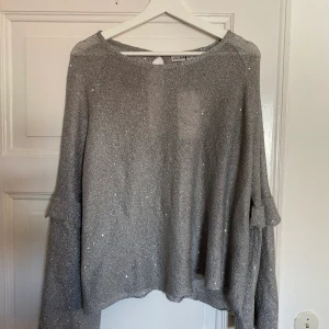 Grå glittrig oversize tröja från Zara i storlek L. - Helt oanvänd topp från Zara i storlek L. Prislappen kvar. Oversize och lite genomskinlig i materialet. Skickar samma dag och uppskattar swishbetalning :) 