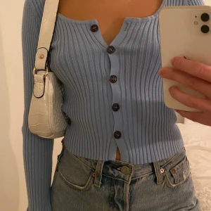 Blå kofta med svarta knappt  - En mjuk blå kofta med svart knappar med volanger längst ner armarna. Köpte den från asos storlek S. 