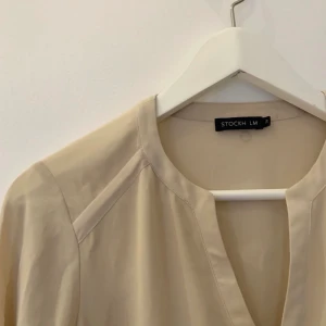 Blus STOCKHLM - Beige blus från STOCKHLM i storlek 34. Gulddetalj längst ut på armarna. Knappt använd.✨ köparen står för eventuell frakt.☺️