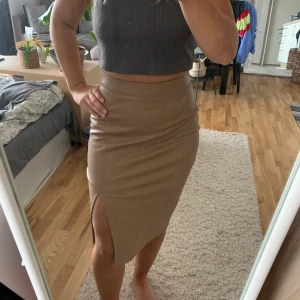 Läderkjol med slits - Oanvänd lite längre kjol i beiget läder med slits vid benet. Storlek 34 så passar XS eller S. Väldigt snygg och framhäver formerna fint, men köpte en lite för liten storlek för mig ✨ från amisu. Frakt tillkommer 