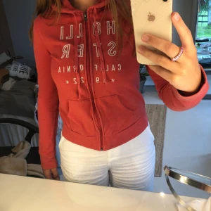 Röd Hollister hoodie - Säljer denna hoodie för jag växt ur den och tröttnat. Använd men bra skick. Står ej för frakt. Den är xs men skulle säga att den passar S också🥰