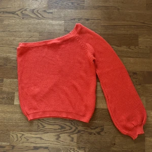 ONE SHOULDER tröja  - En jättefin korallorange färgad one shoulder tröja från NAKD. Ärmarna är jättefin i en mindre ”ballongärm”. Tröjan är superskön. Storlek XS men stor i storleken så funkar upp till M. 
