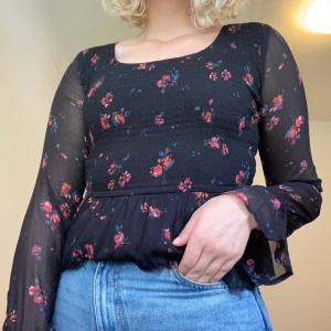 Svart blommig topp - Denna toppen har innan varit en klänning som jag klippt av. Säljer den då jag inte använder den längre men tycker verkligen den är super fin. Kan behövas fixas lite där jag har klippt men inget stort. Köparen står för frakt 