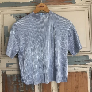  - Silver/skimmer topp med blå ton från bershka. Jättefint skick och toppen på kalas som till att pigga upp vardagen med. Swish eller kontant. Kan antingen mötas upp i stockholm eller rosersberg/märsta, eller frakta. Köparen står för frakten. 