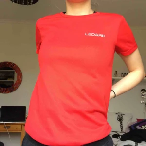  - Röd träningströja som det står ledare på! Väldigt bekväm och gjord i sportmatrial 