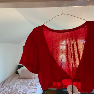 Röd croppad T-shirt - Oanvänd röd croppad T-shirt med djup rygg från nakd! Köparen står för frakt 