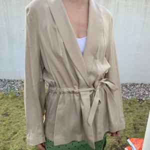 Beige kavaj med skärp - Kavaj från H&M, passar S/M. Går att knyta tajtare elr lösare!!! Köparen står för frakt 