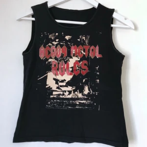  - Svart linne/topp med text i glittrigt röd. ”Heavy Metal Rules”! Skulle gissa storlek XS-S, töjbart tyg, kan säkerligen användas som kortare tröja/magtröja för en större storlek.  M, 34, 36, 38.  Kan mötas i Stockholm eller skicka mot fraktkostnad! ✨🌸✨