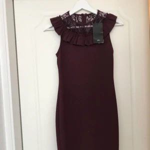  - Röd klänning som slutar vid knäskålarna, med fina detaljer vid bröstet! Aldrig använd med prislapp kvar!