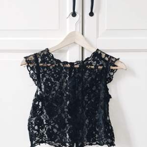 Söt topp i svart lace, cropped fit så passar bra till kjol eller byxor med hög midja. Knappar bak. 