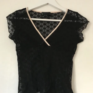  - Kortare svart transparent spetströja med kant av babyrosa siden. Passar nog XS-S. Aldrig använd!