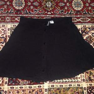 En kort svart kjol med knäppning på framsidan från H&M. Sparsamt använd. På den andra bilden ser den lite gråaktig ut men den är svart:) 