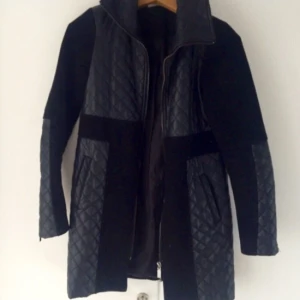  - Snygg svart, TJOCK kappa som håller värmen tills det är dags för vinterjacka! Snygga läderdetaljer och bra passform. Längd: låren/halvvägs till knäna.