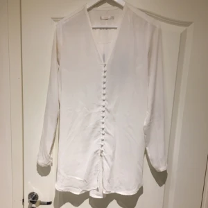  - Längre, vit blus från Wera Åhléns i storlek 38. 