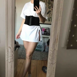  - Säljer denna långa T-shirt tillsammans med korsetten. Går även att endast köpa T-shirten för sig eller korsetten. Jättesnyggt att ha T-shirten tillsammans med en blazer;) Köparen står för frakten, 79kr