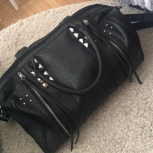  - svart väska med väldigt snygga detaljer. Sitter ett axelband på men det går att ta bort. Hör av er vid intresse