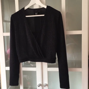  - Superglittrig croptop som är perfekt till höga jeans eller kjol och klackar! Den stängs med en liten hake mellan brösten och passformen är ganska lös!