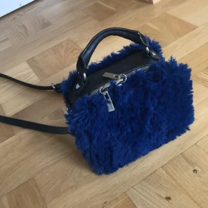  - Liten väska i blå fuskpäls. Finns ett justerbart band! Mycket bra skick!