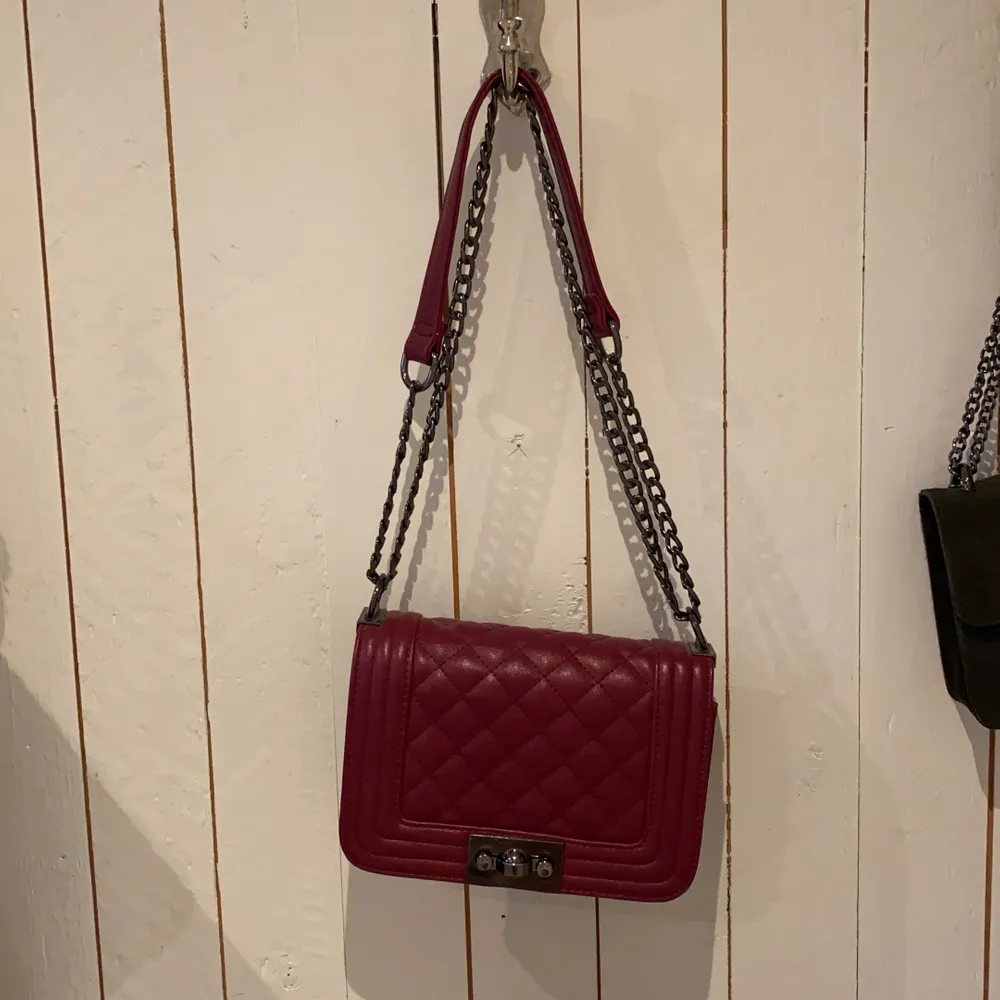 Axelbands väska som inte kommer till användning. Färgen är en blandning mellan rosa/röd. Väskor.