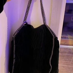 Stella McCartney -  Säljer en mycket fin och unik Stella McCartney väska! Nypris: ca 9000kr  Modell:  ”Falabella Tote fringed black” och är svart med svarta fransar.  Obetydligt använd och i utmärkt skick! Inget slitage varken in-eller utvändigt, inga repor och ser princip som ny ut!  Säljs eftersom jag fick den i julklapp, men vill hellre ha pengarna till något annat. Hoppas väskan får en ny ägare, tveka inte på att höra av dig till mig! 👜👛❣️❣️ skriv privat för fler bilder!