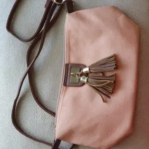 Crossbody väska i rosa med bruna och guldfärgade detaljer.