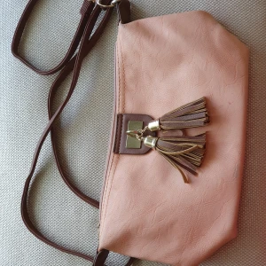Crossbody väska - Crossbody väska i rosa med bruna och guldfärgade detaljer.