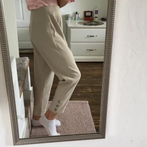  Byxor  - Jättefina beiga kostymbyxor med en dragkedja på sidan och bruna knappar på benen. Dem har använts 2 gånger men dem är i en väldigt bra skick och har inga fläckar eller slitningar. Dem är jätte sköna och har en väldigt bra material. Köparen står för frakt💕