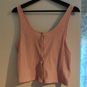 Ribbat crop-linne strl L - Skönt och gulligt linne med knappar framtill. Endast testat, lappen sitter kvar. Kan skickas, då betalar köparen frakten (priset kan dock diskuteras).