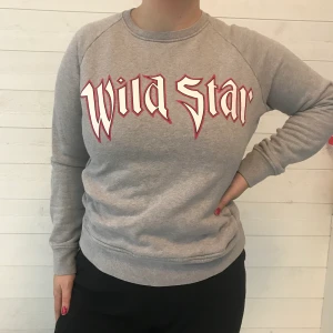 Grå collegetröja med tryck - Gråa collegetröja från märket Rika (by Ulrika Lundgren). Tryck på bröstet där det står ”wild star” och fickor på varje sida om magen! Storlek XS men jag som vanligtvis är M kan också ha den! Frakt tillkommer!
