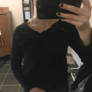 Fin topp - Svart långärmad tröja med fin detalj i ringningen! Liten volang. 