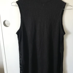 Ribbat polo-linne  - Ett svart ribbat polo-linne med slits 