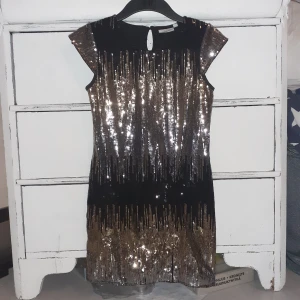 Glittrig klänning  - En svart klänning med mycket glitter på framsidan! Går ned till knänen på en! En perfekt klänning till nyår 