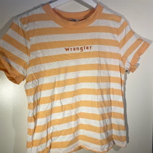 Wrangler t-shirt  - Orange/vit randig t-shirt med logga mitt på bröstet. Köpt på Carlings