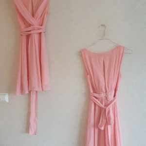 Corallrosa klänningar (2 st finns) - Corallrosa chiffong klänning köpt på MQ för 499:-, Märke: Zoul. Det finns 2 exemplar som har använts en gång som tärnklänningar på bröllop. Superbekväm och sitter snyggt på alla olika kroppar (vi var 4 st med helt olika kroppsform och den satt snyggt på alla oss). Bandet kan knytas på olika sätt, en smal öppning i ryggen som går att sätta ihop med säkerhetsnål om man vill ha vanlig bh under (jag använde dock free-bra under min). Klänningen täcker ca 3/4 av låren - nästan till knäna (en mycket fin längd).  Storleken är 32 men bpda jag som är en mindre 32 och min kompis som är en större 34 kunde ha samma storlek då den formar sig bra efter kroppen. 150 kr st eller 200 kr paketpris för båda.