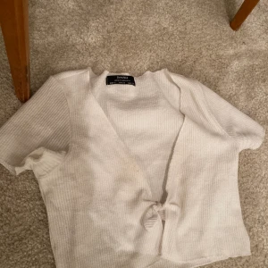 Liten crop top - Crop top med knytning fram. Använd 1 gång. I ribbat material. Slutar under brösten. 
