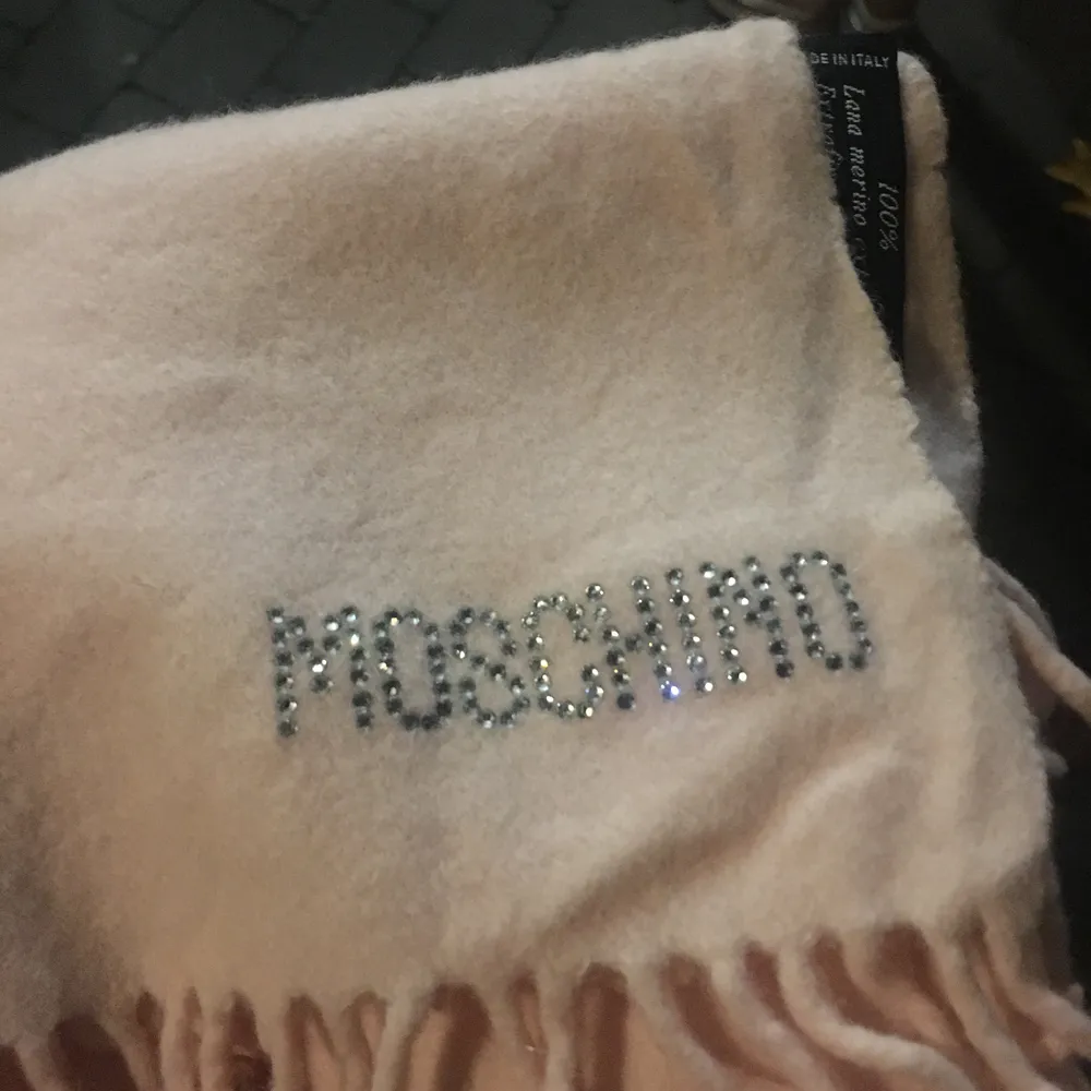 ÄKTA!! Unik moschino halsduk som är gjort av ull, MOSCHINO skrivit med strass 💓.  Likadan scarf i svart är värderad till 2000kr. Accessoarer.