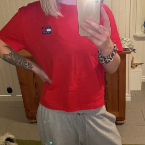 T-shirt från Tommy Jeans - Röd T-shirt som är lite kortare i längden. Använd fåtal gånger. Köptes för 499kr.