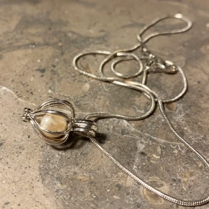 Halsband med 18 karats guld och äkta pärla - En personlig och fin julklapp till någon du älskar! Halsbandet är oanvänt och i bra skick. 18 karat guld (står på halsbandet + har fått bekräftat av värderare). Äkta pärla inuti smycket.❤️🎅🏼 Buda på priset. (Skickas med spårbar frakt).