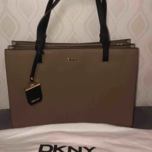  - Beige Dkny väska (ÄKTA). Nypris 3300kr säljs 1500kr Nyskick, vid intresse finns fler bilder! 