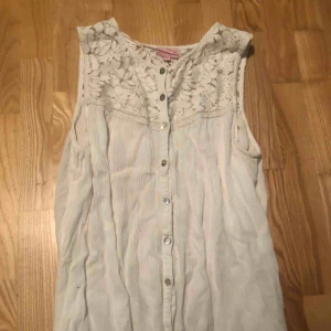 - Säljer en fin vitt somrig topp. Den är ett linne och har spets upptill. Den är i storlek 158/164 men passar också XS 