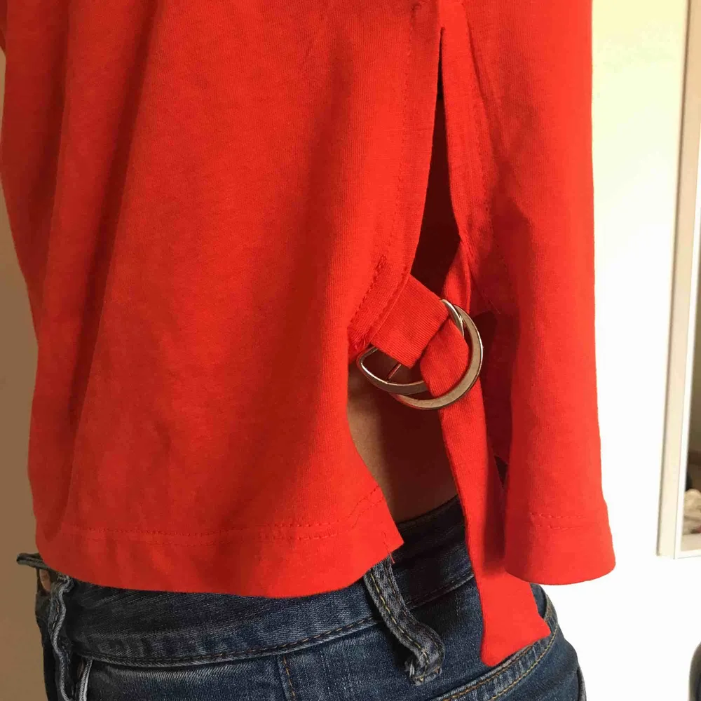 En röd t-shirt med detaljer på sidorna med band och metall. Kostar 150kr inklusive frakt.. T-shirts.