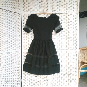  - Sjukt snygg klänning med åtsittande midja och något utställd kjol. Svart med transparenta meshränder. 
Aldrig använd.