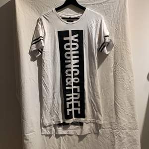 Vit unisex oversize T-shirt med texten ”Young and free” på framsidan och ”fearless” på ryggen. Den är inte särkilt bred men är längre. Plagget är i nyskick