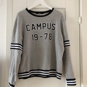 Collegetröja - Grå collegetröja med svarta ”sport” detaljer. Väldigt skön inuti, men säljer pga använder inte. Storleken är L men passar även M. Står ej för frakt