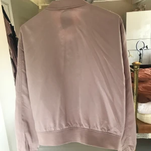 Rosa bomberjacka med rosé detaljer  - Jacka i stl L men sitter som en M. Knappt använd. Frakt kostnad tillkommer om ni inte kan mötas upp! 