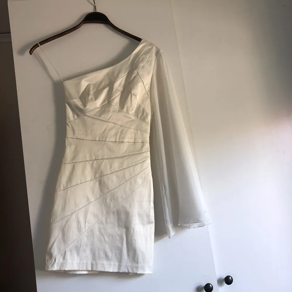 Vit figursydd klänning i stabilt silke med transparent ärm. Endast använd en gång. Hämtas i Motala eller skickas mot frakt. . Klänningar.