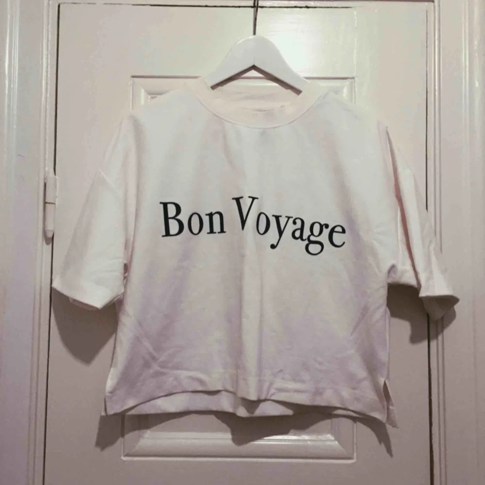 Vit t-shirt men text där de står Bon voyage, . Skjortor.