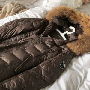  - Medellång & figursydd jacka från Rockandblue i strl 34 som håller värmen bra under vintern. Använt endast några få gånger förra vintern då det inte är min stil. Äkta tvättbjörnspäls. Tillhörande bälte & dustbag medföljer. Köpt för 3699 kr. Frakt ingår