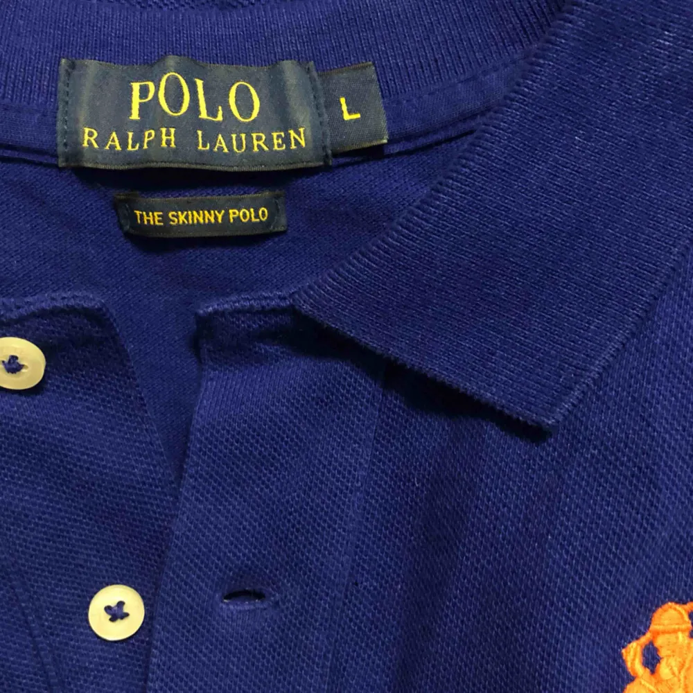 Mörkblå Ralphlaurenpolo med orange logga. Frakt ingår! Prutbart vid snabb och smidig affär. . T-shirts.