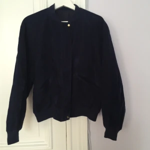  - Mjuk marinblå bomberjacka med guldknappar på framsidan 